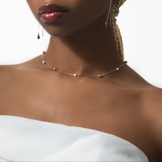 Close-up of a woman wearing a gold necklace with pearls on a white background