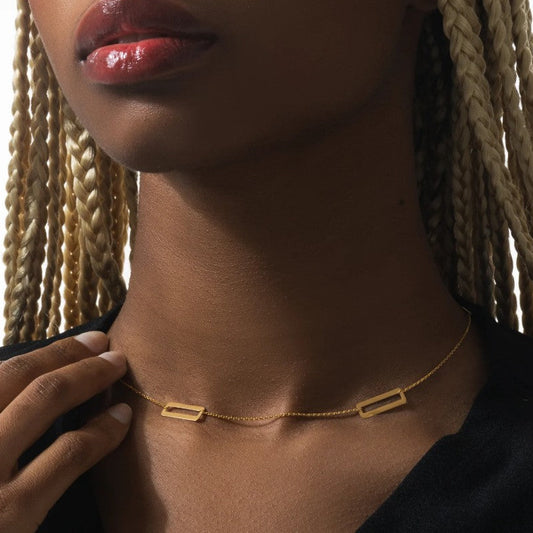 Close-up of a person wearing a gold necklace with braided hair.