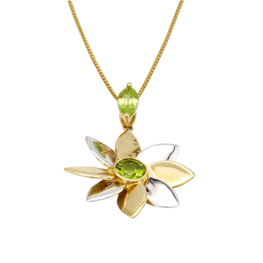 Yellow and white gold pendant with green gemstones on a white background