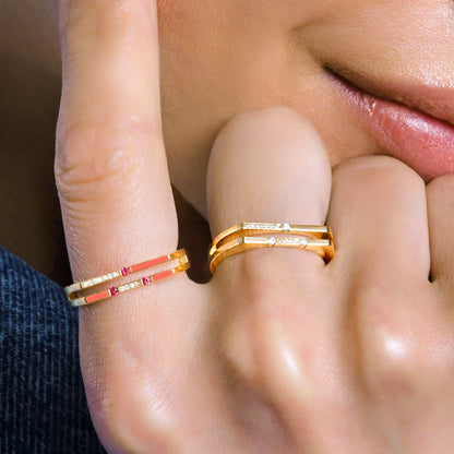 Close-up of a hand wearing two gold rings with red stones.