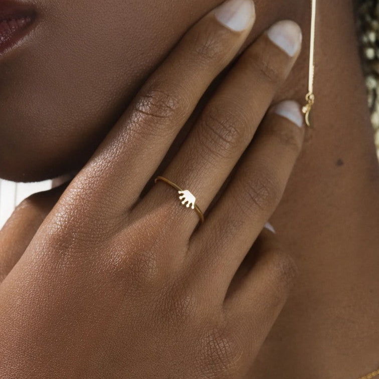 Close-up of a hand wearing a gold ring with a leaf design.