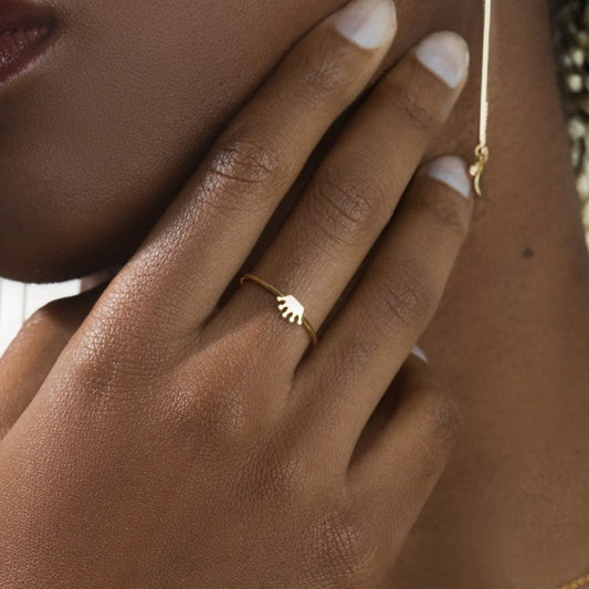 Close-up of a hand wearing a gold ring with a leaf design.
