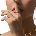 Close-up of a woman's hand wearing a gold ring and bracelet on a white background