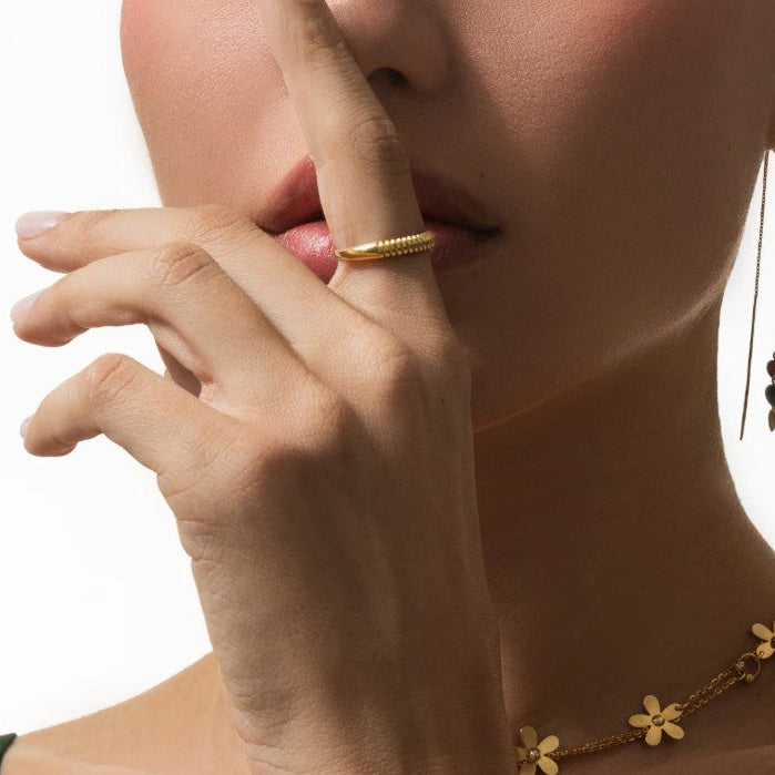 Close-up of a woman's hand wearing a gold ring and bracelet on a white background