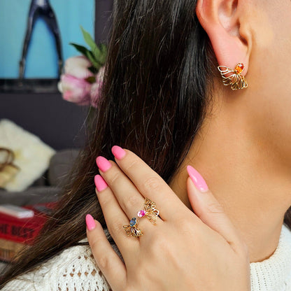 Close-up of a woman wearing gold earrings and ring with gemstones, indoors.
