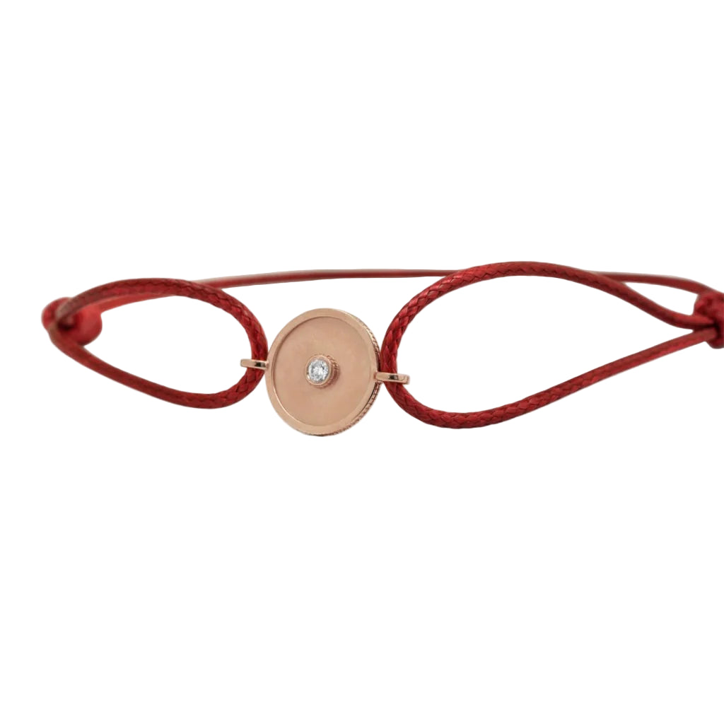 Red bracelet with a gold circular charm on a white background