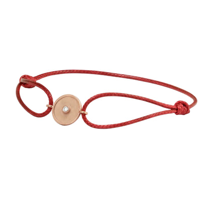 Red bracelet with a gold circular charm on a white background