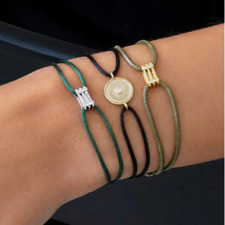 Close-up of a person's wrist with multiple bracelets on a neutral background