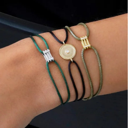 Close-up of a person's wrist with multiple bracelets on a neutral background