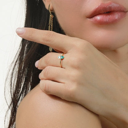 Close-up of a person wearing a gold ring with a green gemstone on a neutral background