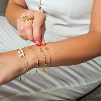 Close-up of a person's arm wearing multiple gold bracelets and rings.