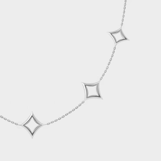 White gold necklace with star-shaped pendants on a light gray background