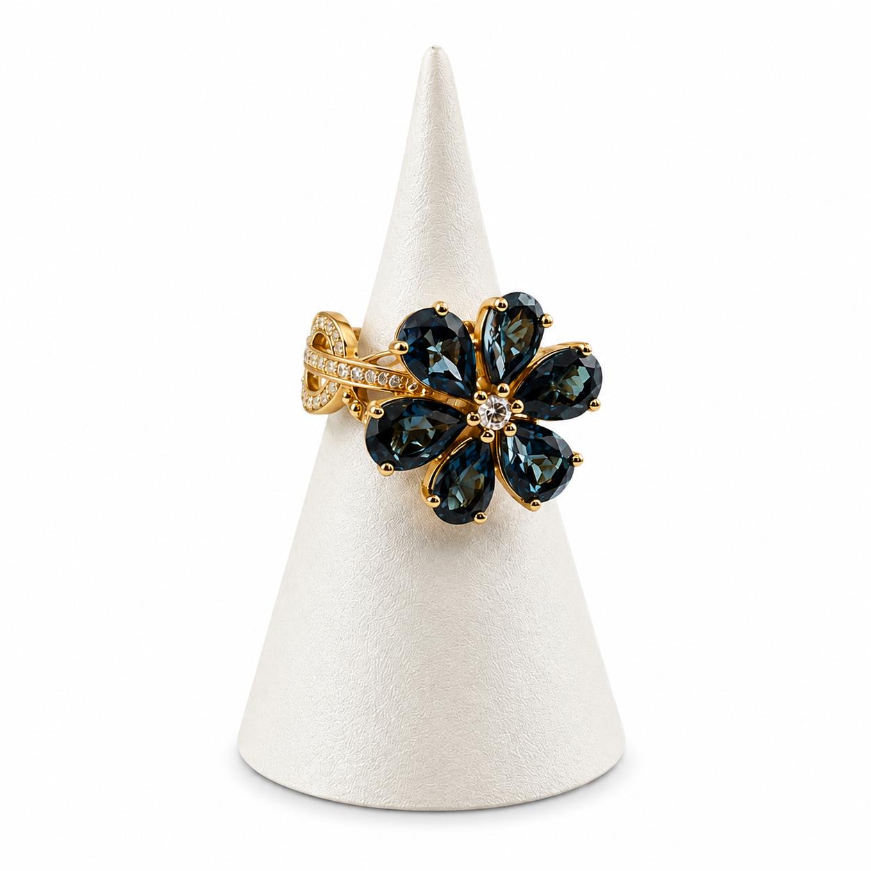 Gold ring with green gemstones on a white cone stand against a white background