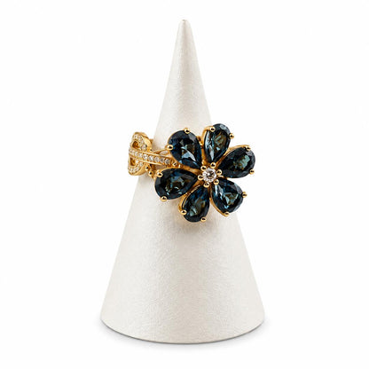 Gold ring with green gemstones on a white cone stand against a white background