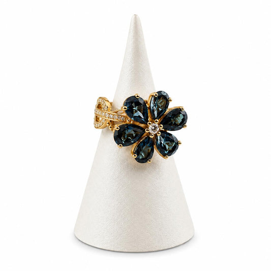 Gold ring with green gemstones on a white cone stand against a white background