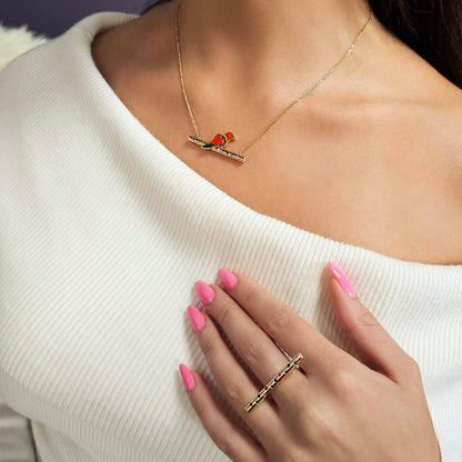 Necklace with a small red bird pendant worn by a person in a white sweater.
