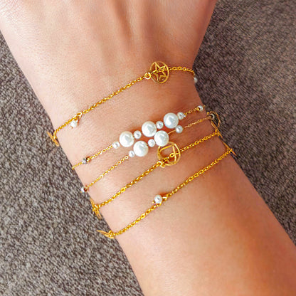 Gold anklets with pearl beads on a person's ankle against a brown background