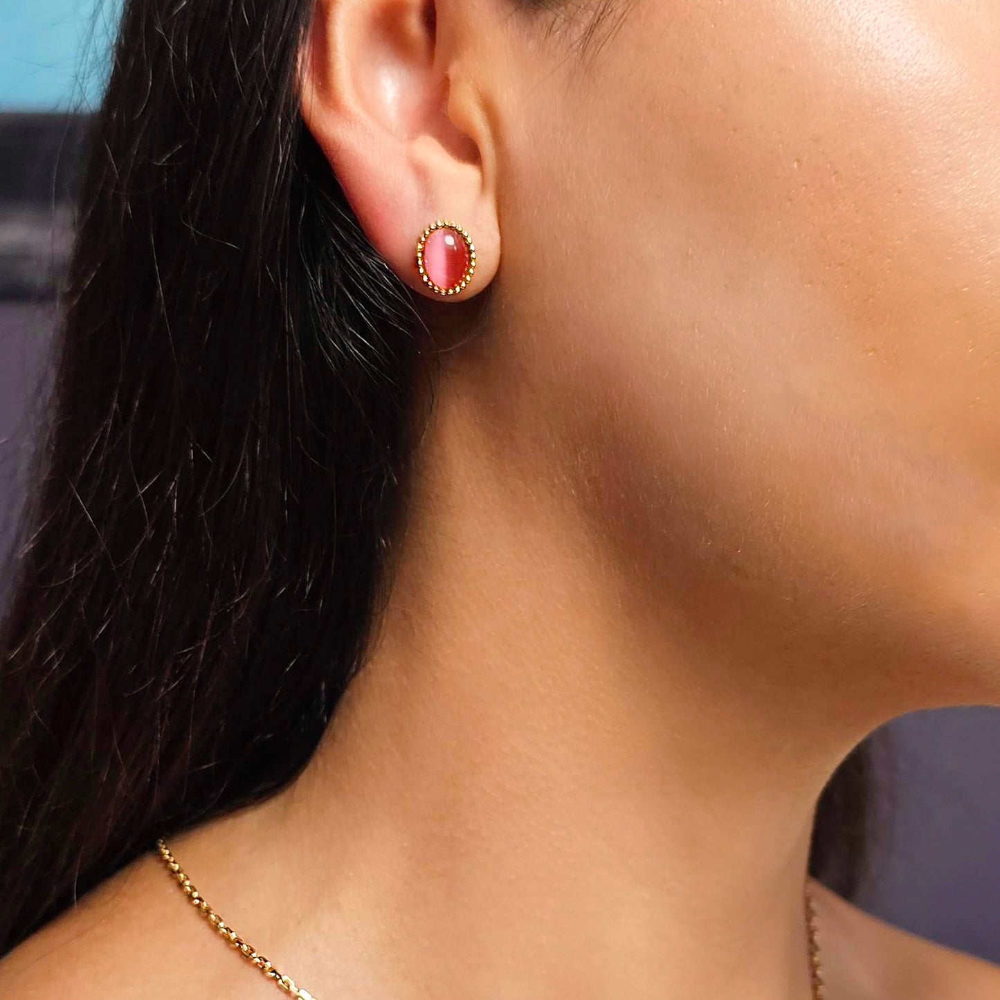 Close-up of a person wearing a red earring with gold accents.