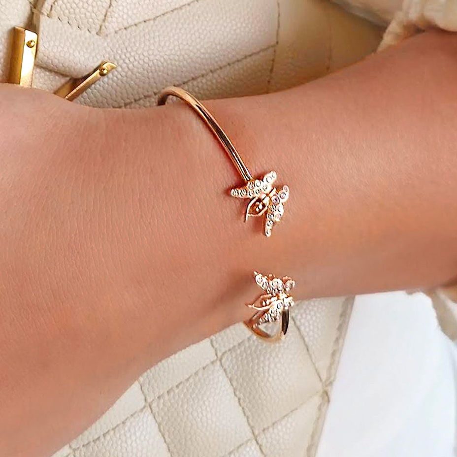 Rose gold bracelet and ring set on a wrist against a neutral background