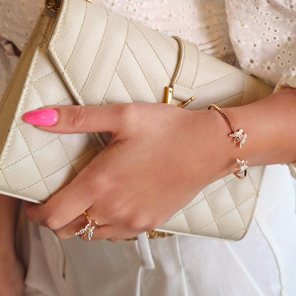 Close-up of a hand holding a beige quilted handbag with pink nail polish and gold jewelry.