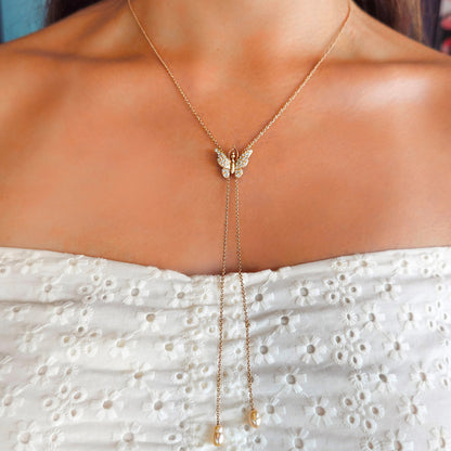 Gold butterfly necklace on a person wearing a white dress