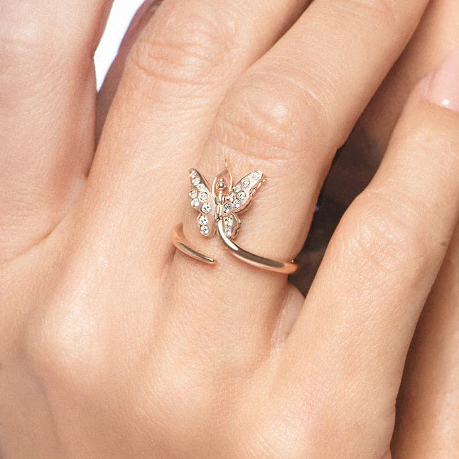 Close-up of a woman's face with one hand covering her eye, wearing a rose gold ring with a diamond.