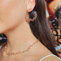 Close-up of a person wearing gold hoop earrings and a matching necklace.