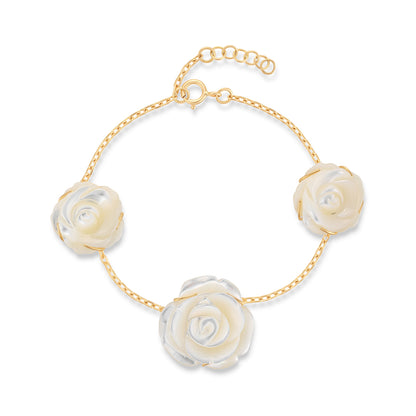 Bracelet with white rose-shaped charms on a gold chain against a white background