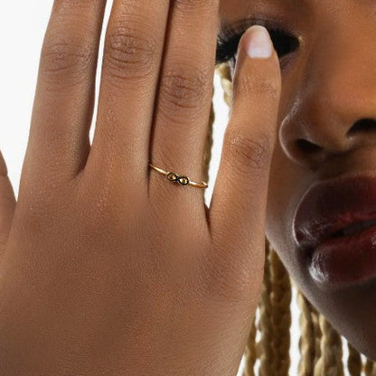 Close-up of a hand wearing a gold ring with a blurred background