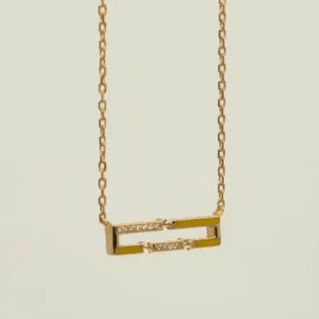 Gold necklace with a rectangular pendant on a light beige background