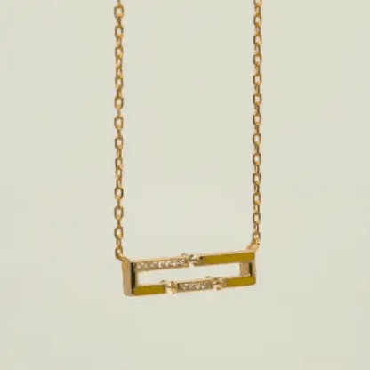 Gold necklace with a rectangular pendant on a light beige background