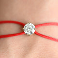 Bracelet with a diamond on a red cord against a blurred background
