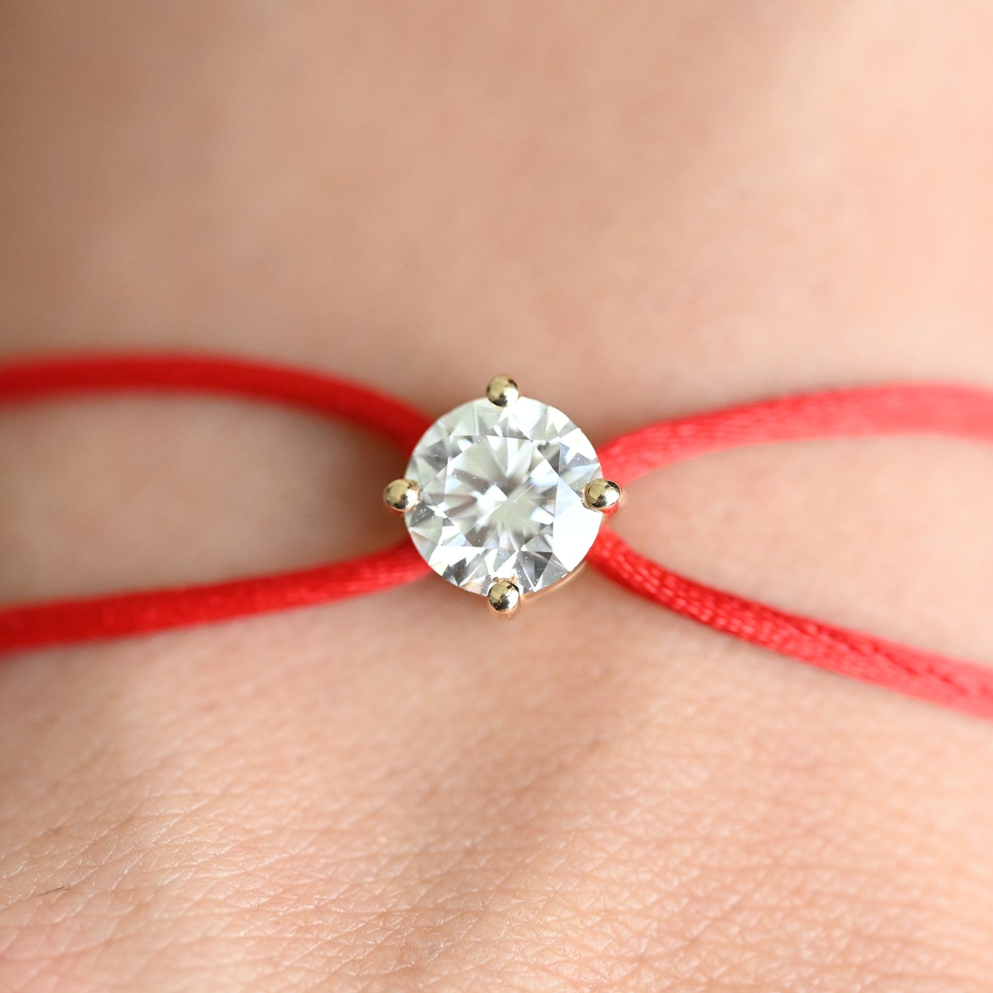 Bracelet with a diamond on a red cord against a blurred background