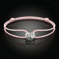 Pink bracelet with a clasp featuring two clear stones on a black background