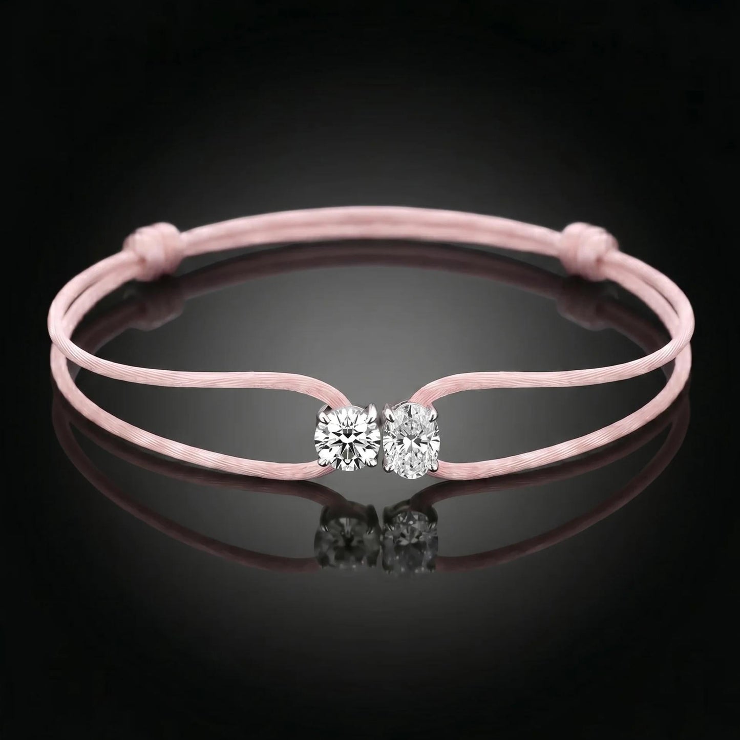 Pink bracelet with a clasp featuring two clear stones on a black background