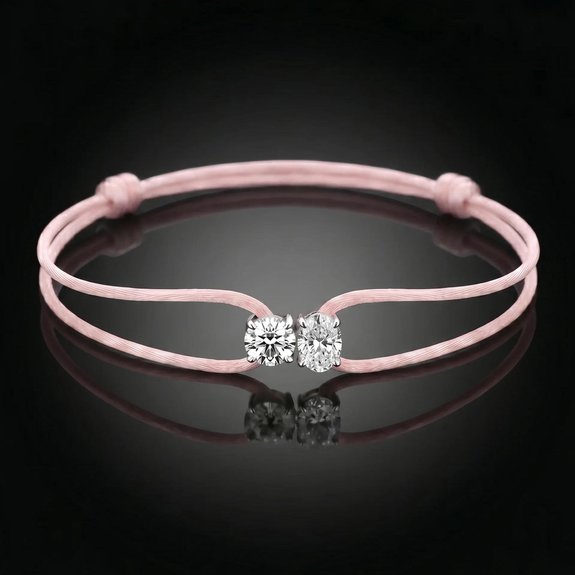 Pink bracelet with a clasp featuring two clear stones on a black background