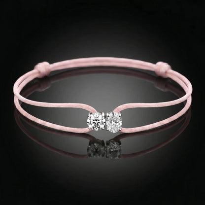 Pink bracelet with a clasp featuring two clear stones on a black background