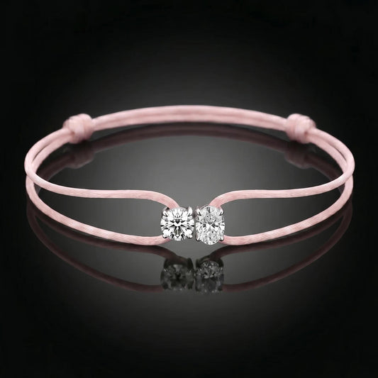 Pink bracelet with a clasp featuring two clear stones on a black background