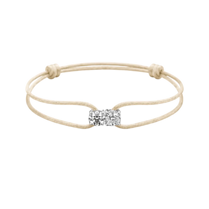 Beige bracelet with a diamond bow charm on a white background
