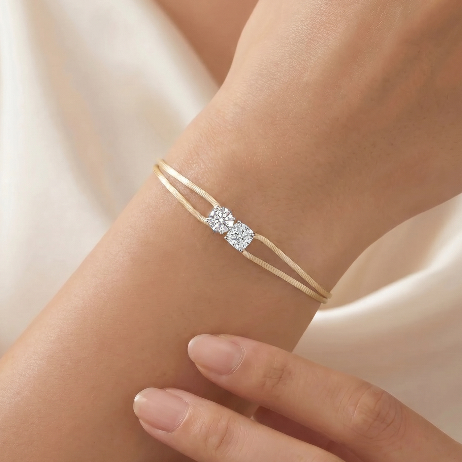 Gold bracelet with a diamond on a wrist against a soft beige background