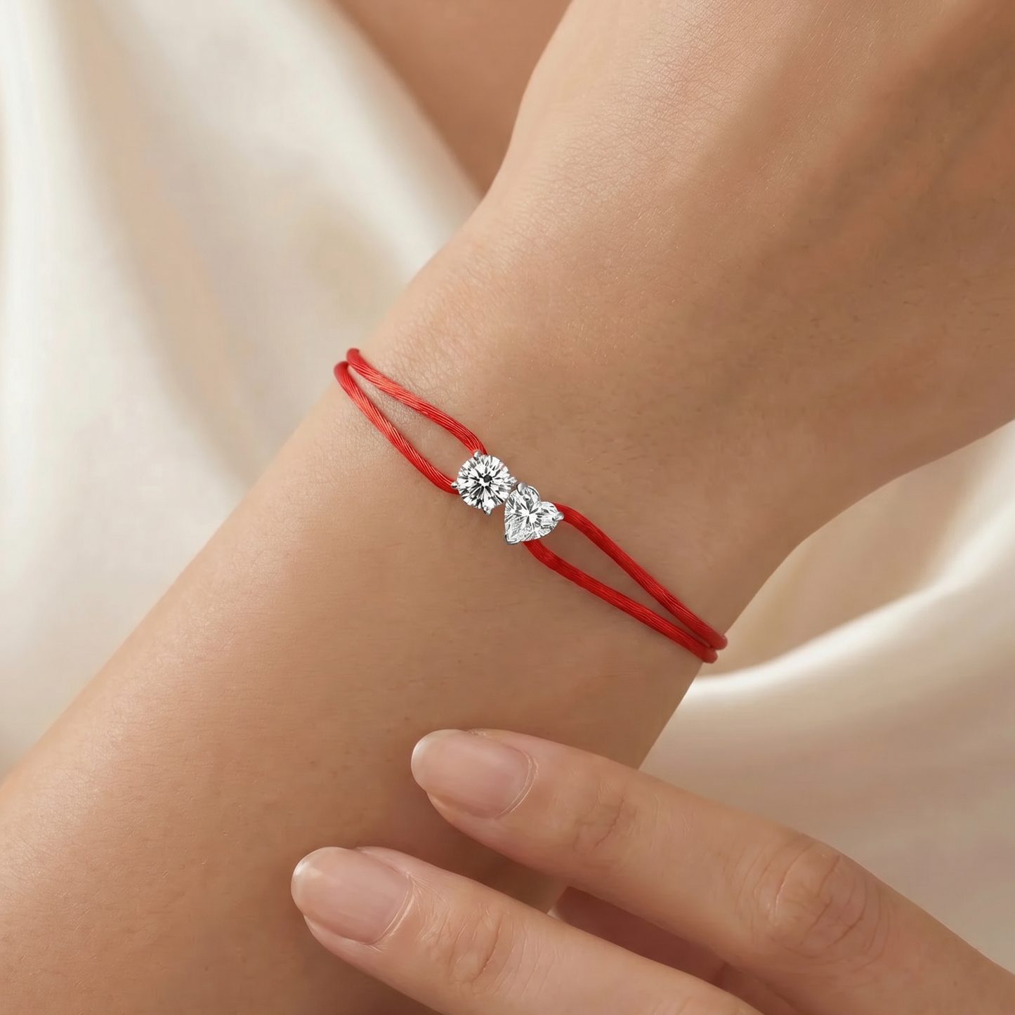 Red string bracelet with a diamond on a wrist against a neutral background
