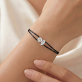 Black cord bracelet with a silver clasp on a wrist against a neutral background