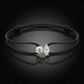 Black cord bracelet with a silver clasp on a dark background
