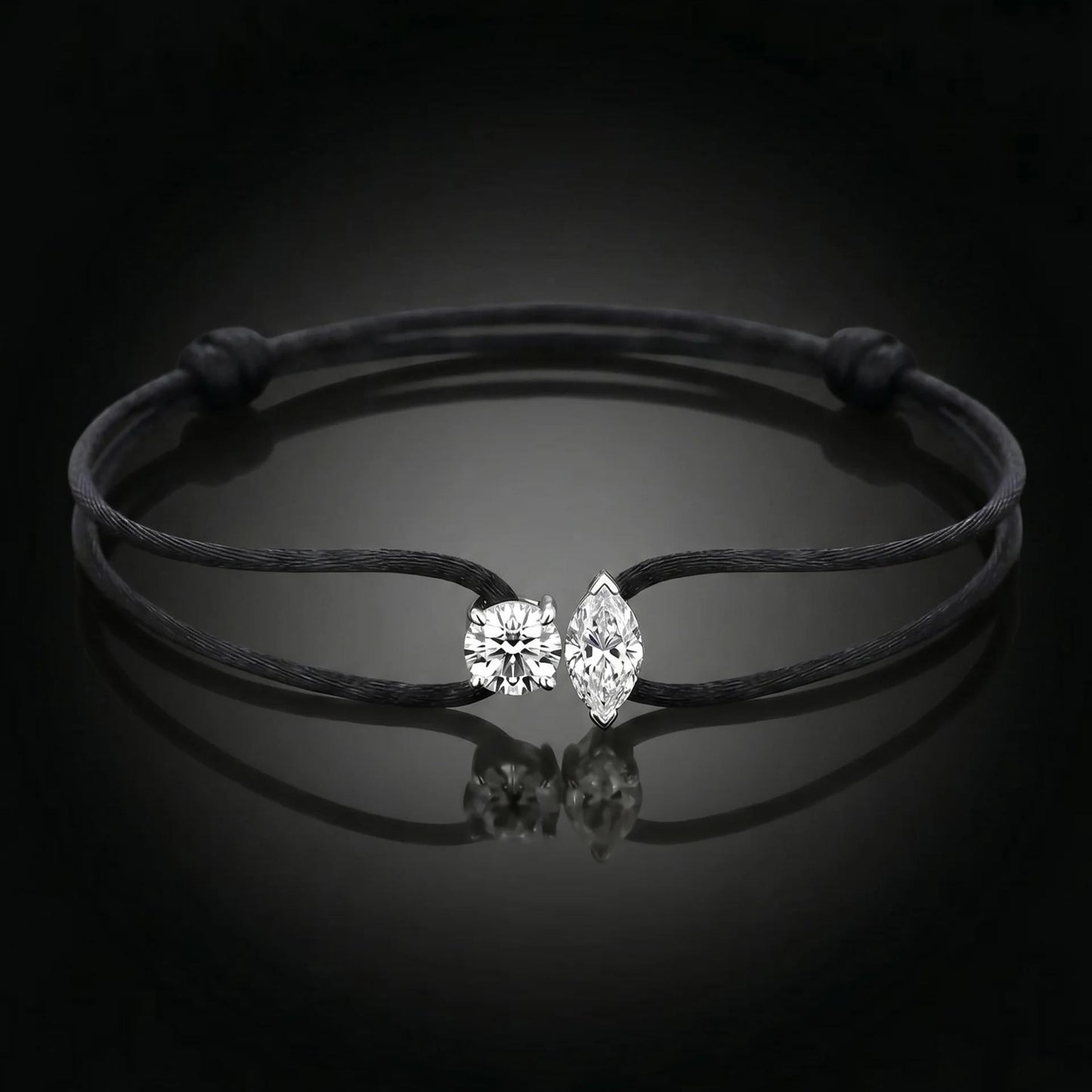 Black cord bracelet with a silver clasp on a dark background