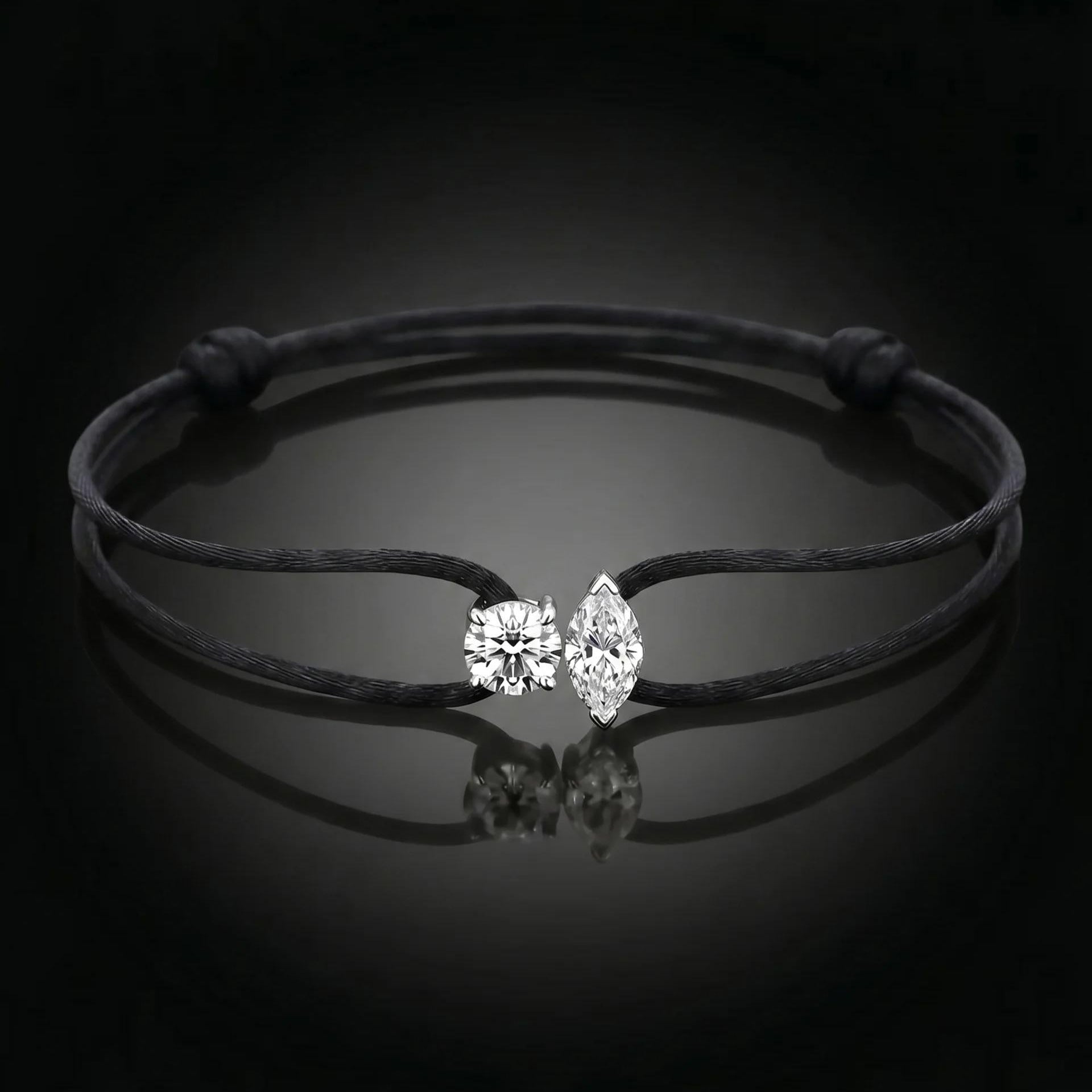 Black cord bracelet with a silver clasp on a dark background