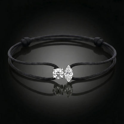 Black cord bracelet with a silver clasp on a dark background