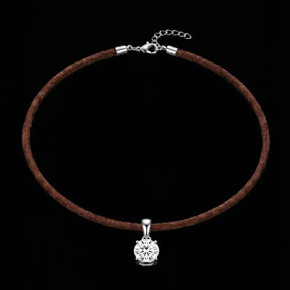 Brown cord necklace with a silver pendant on a black background