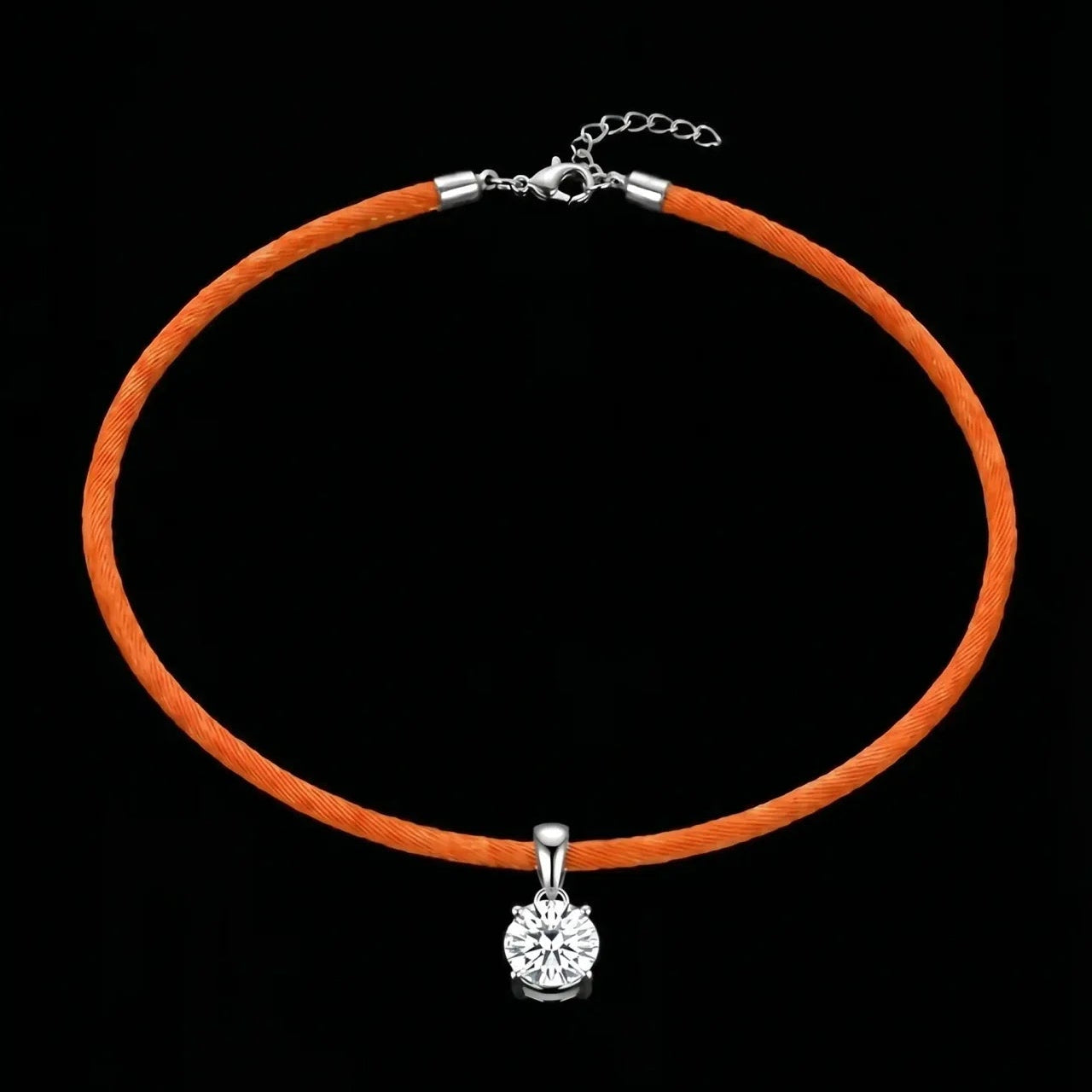 Orange cord necklace with a silver clasp and round pendant on a black background