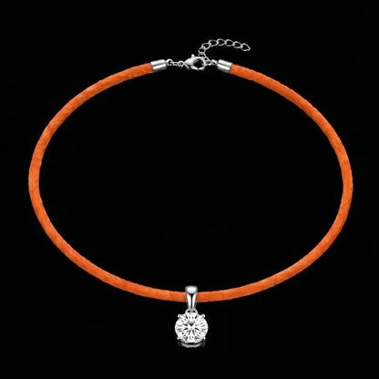 Orange cord necklace with a silver clasp and round pendant on a black background