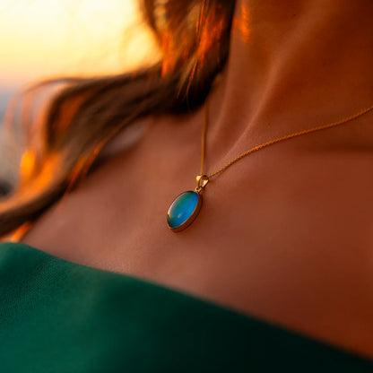 Necklace with a blue pendant worn by a person, with a blurred background